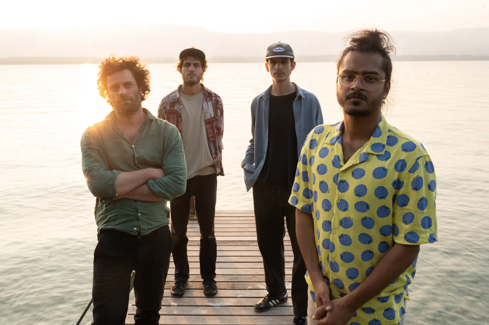 Group portrait of the PROTOTYPE quartet standing on the pier with the sun flaring behind them