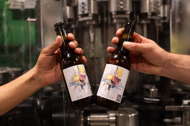 Two bottles of the limited-edition Sunglint beer held up in a brewery